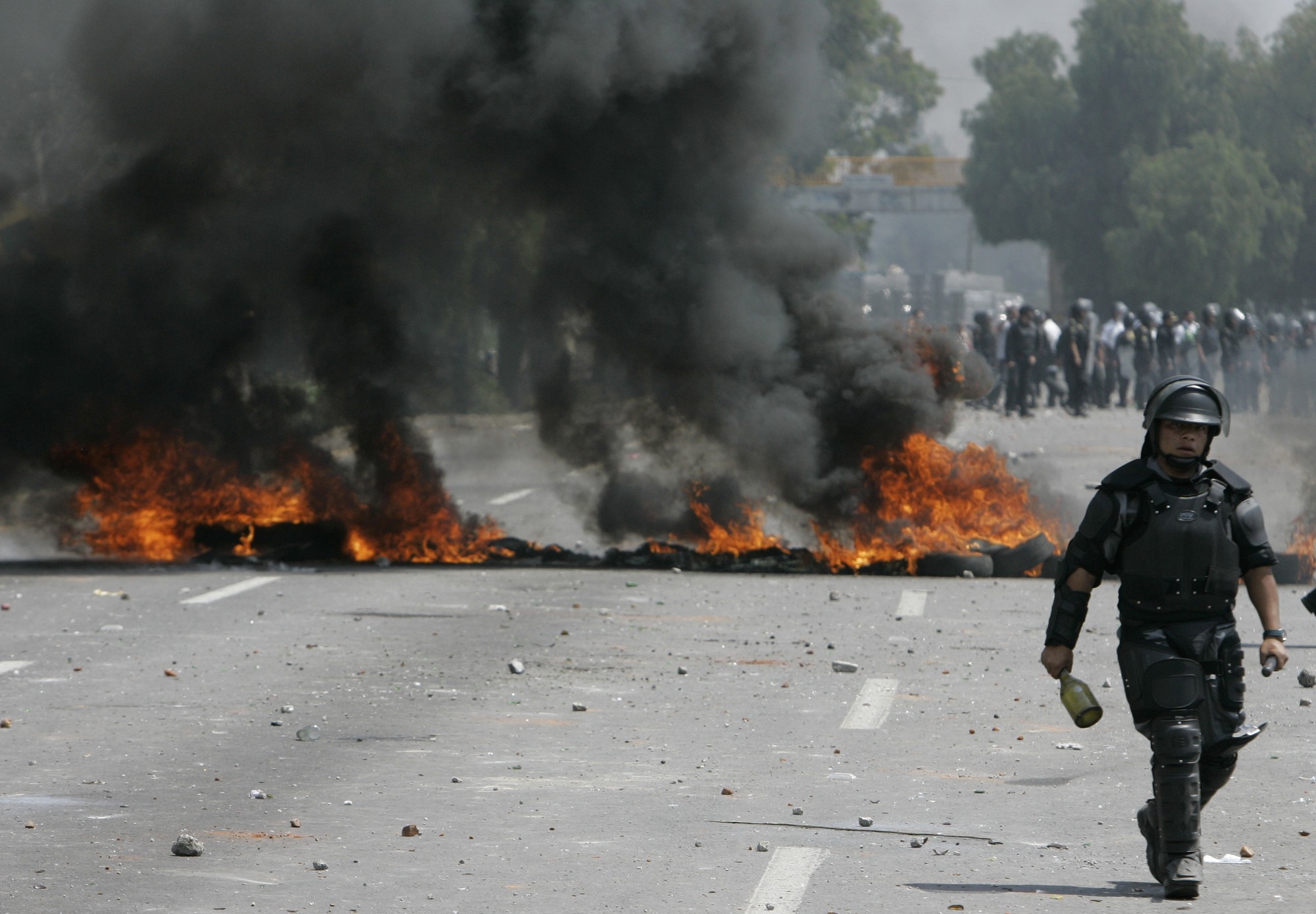 Un policía anti motín del Estado de México pasa junto a una barricada durante el enfrentamiento de Atenco en el año 2006.