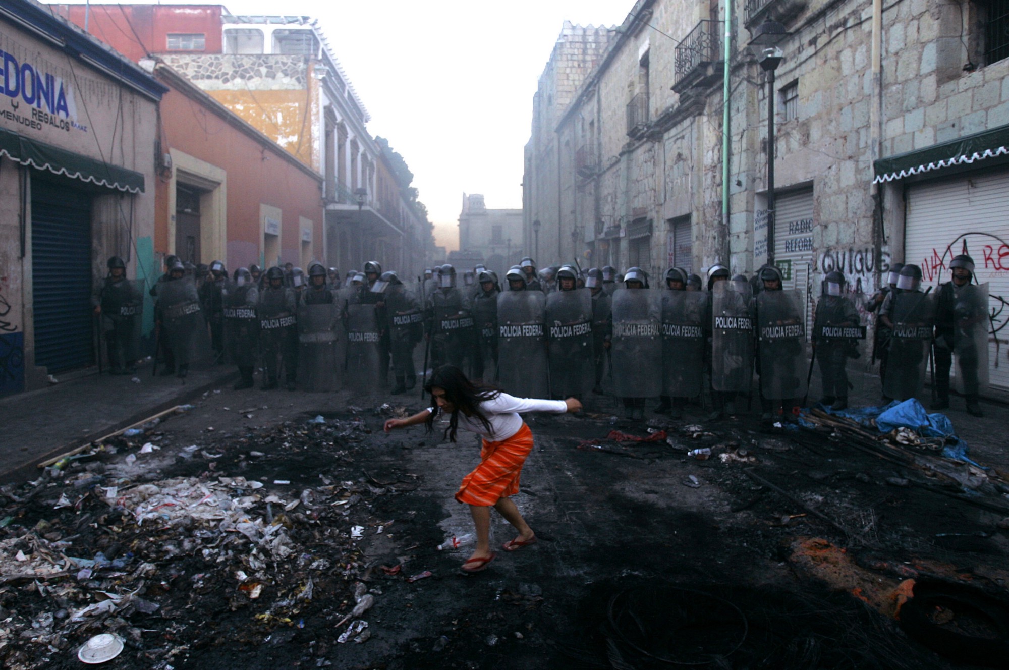 Una mujer pasa frente a un bloqueo de la policía en el centro de Oaxaca de Juárez, Oaxaca. Esto sucedió después de que manifestaciones ocurrieran para exigir la renuncia del gobernador del Estado, Ulises Ruiz.