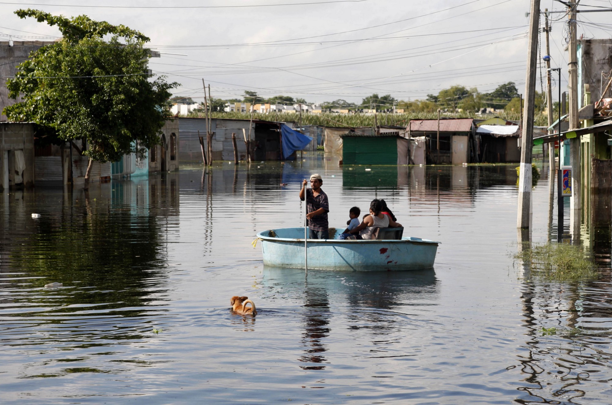 Un pequeño grupo de gente usa una balsa en una avenida inundada en Villahermosa, Tabasco.