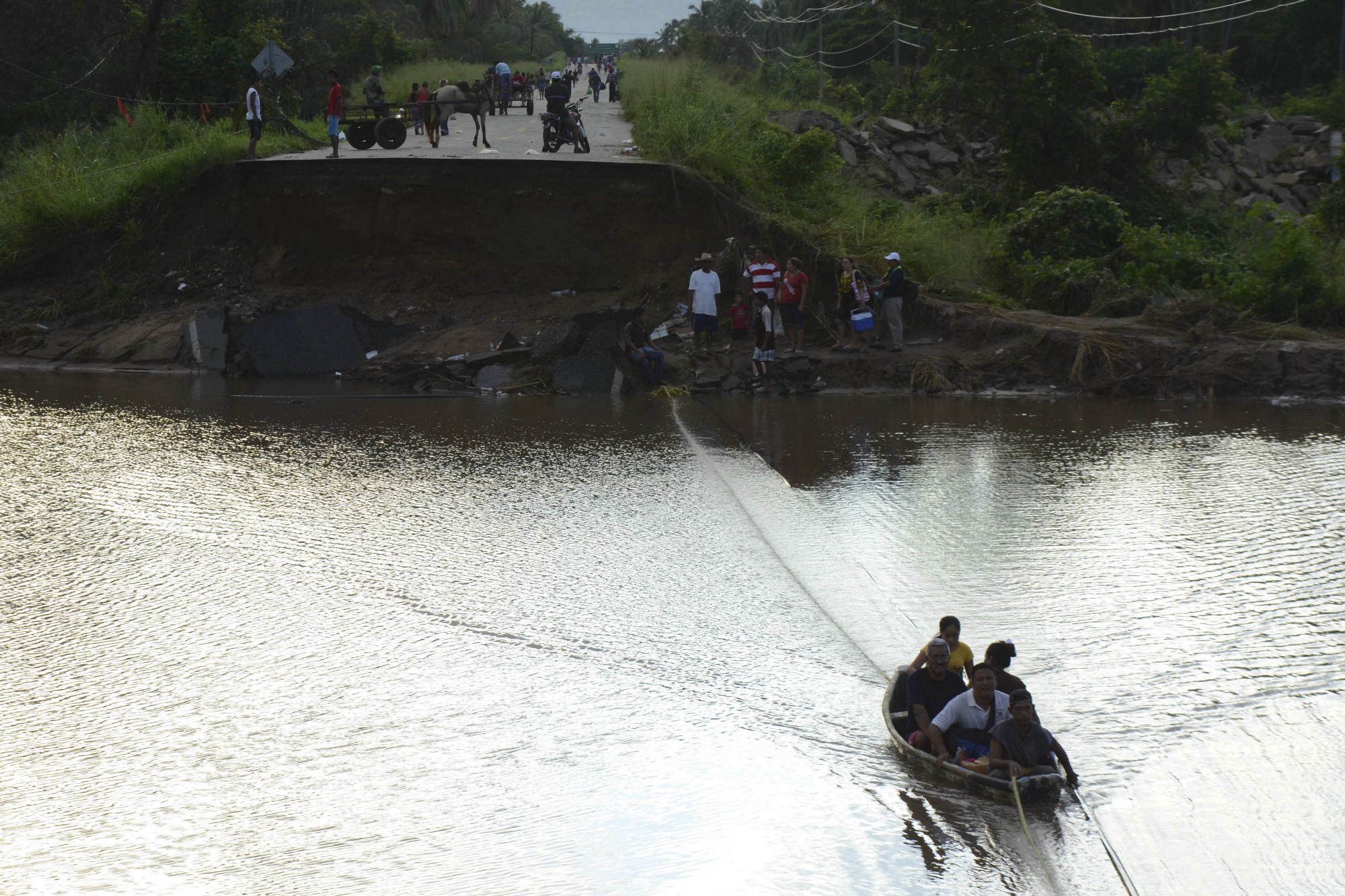 Gente cruza en un bote después de que se colapsara un puente en las cercanías de Atoyac. Esto fue provocado por los huracanes Ingrid y Manuel, que llevaron a la muerte a cientos de personas.