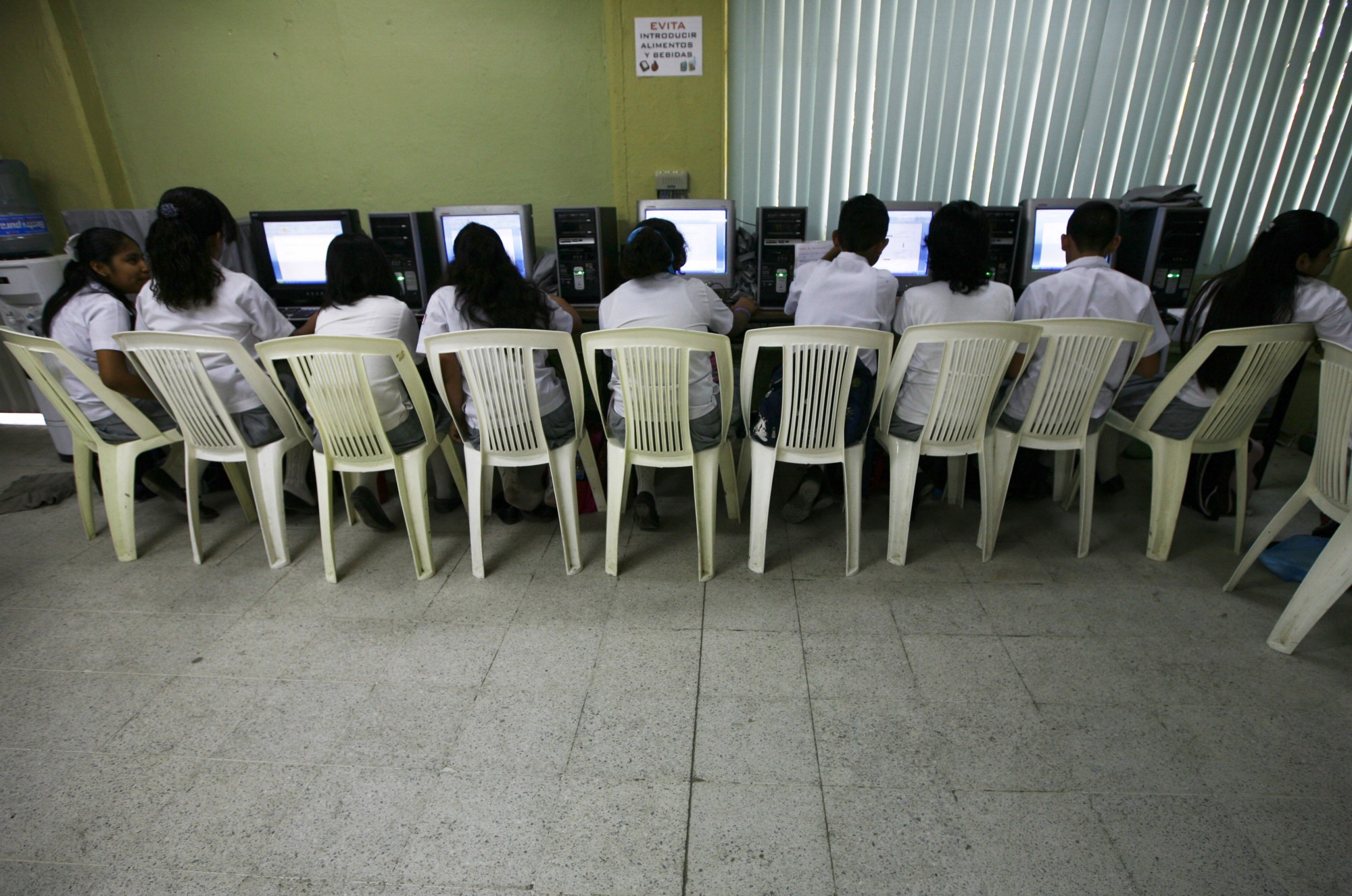 Estudiantes de primaria comparten computadoras para tomar clase.