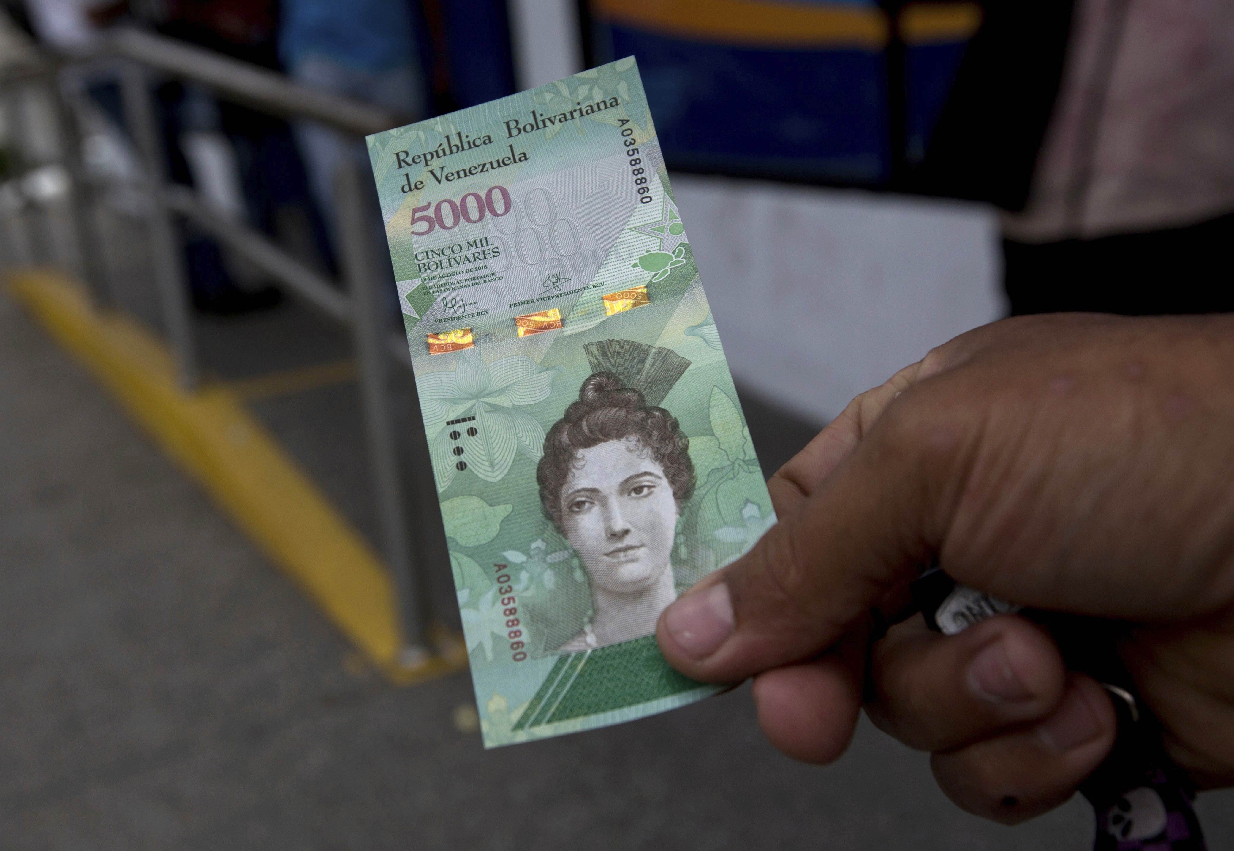 Un hombre muestra un nuevo billete de 5,000 bolívares afuera de un banco en Caracas, Venezuela (AP)