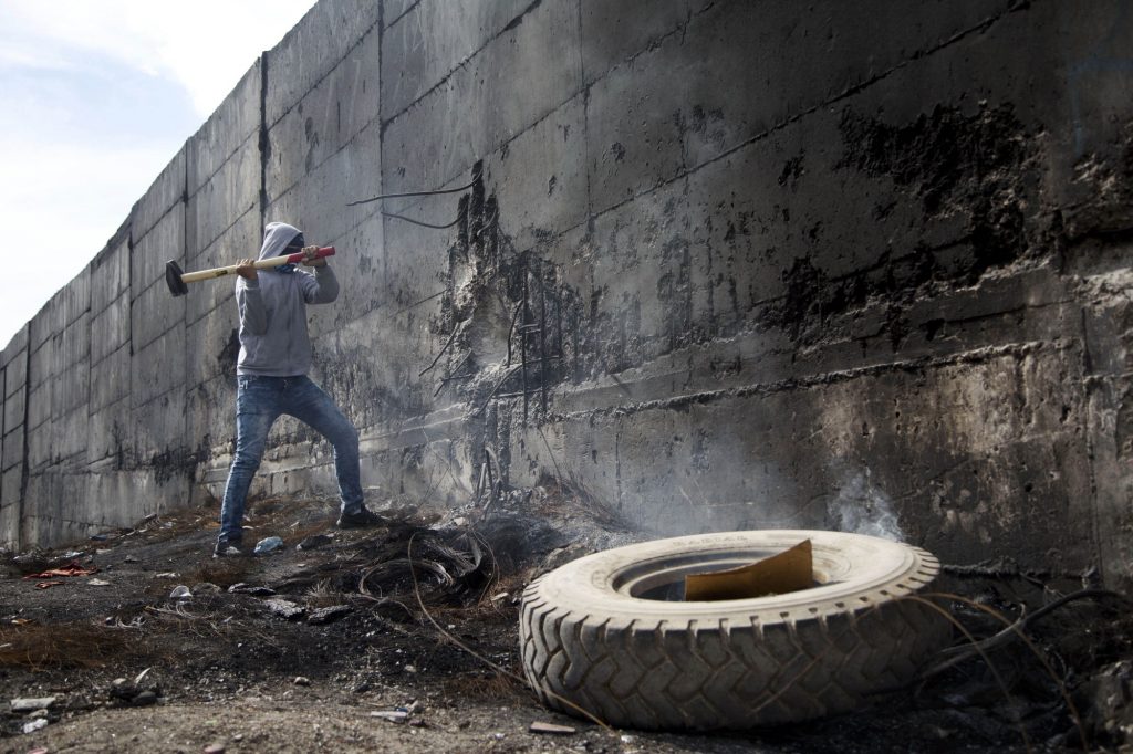Un estudiante intenta romper el muro que separa Cisjordania e Israel