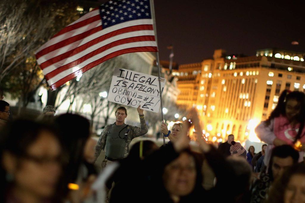 Hombre en protesta se expresa contra Barack Obama con letrero que dice: “¡[Ser] ilegal es un delito! Obama= Coyote #1”