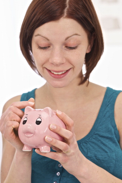 Imagen ilustrativa de una mujer ahorrando su dinero en una alcancía (Getty Images)