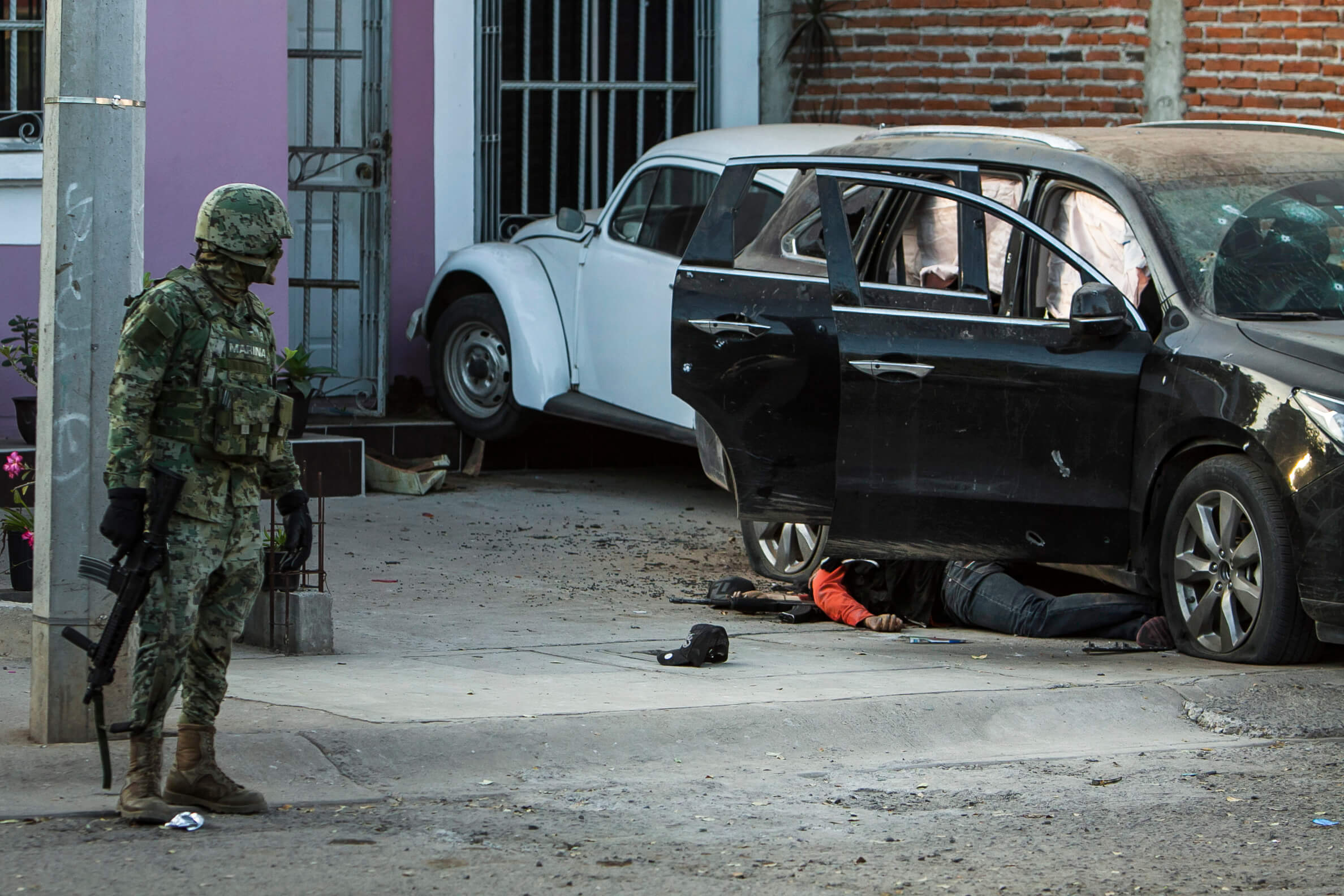 Un marino mira el cuerpo de un hombre al lado de un vehículo, tras un tiroteo en Culiacán, Sinaloa. (AP, archivo)