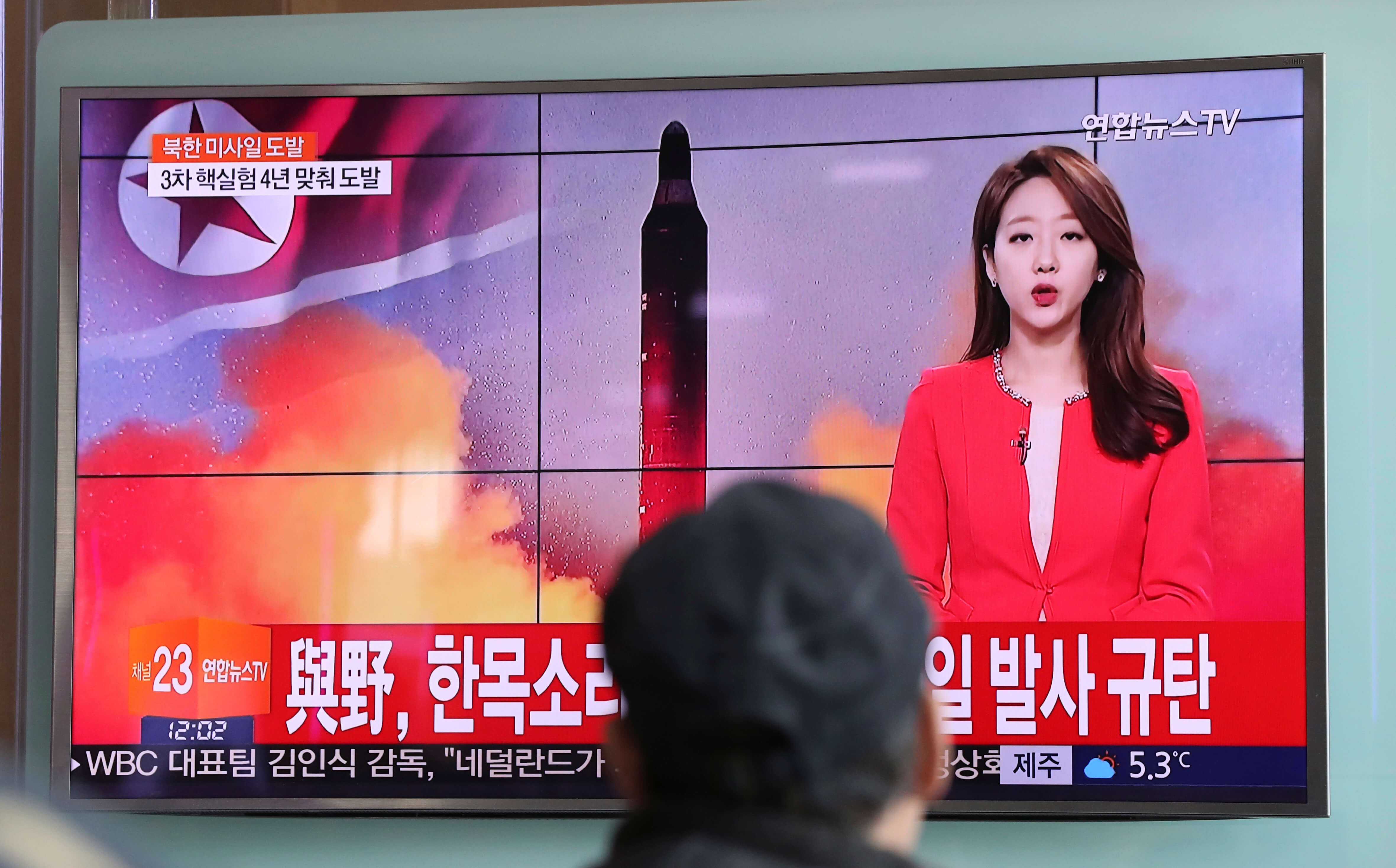 Un hombre observa un noticiero en el que se informa del lanzamiento de misiles de Corea del Norte, con una imagen de archivo de un misil norcoreano. (AP)