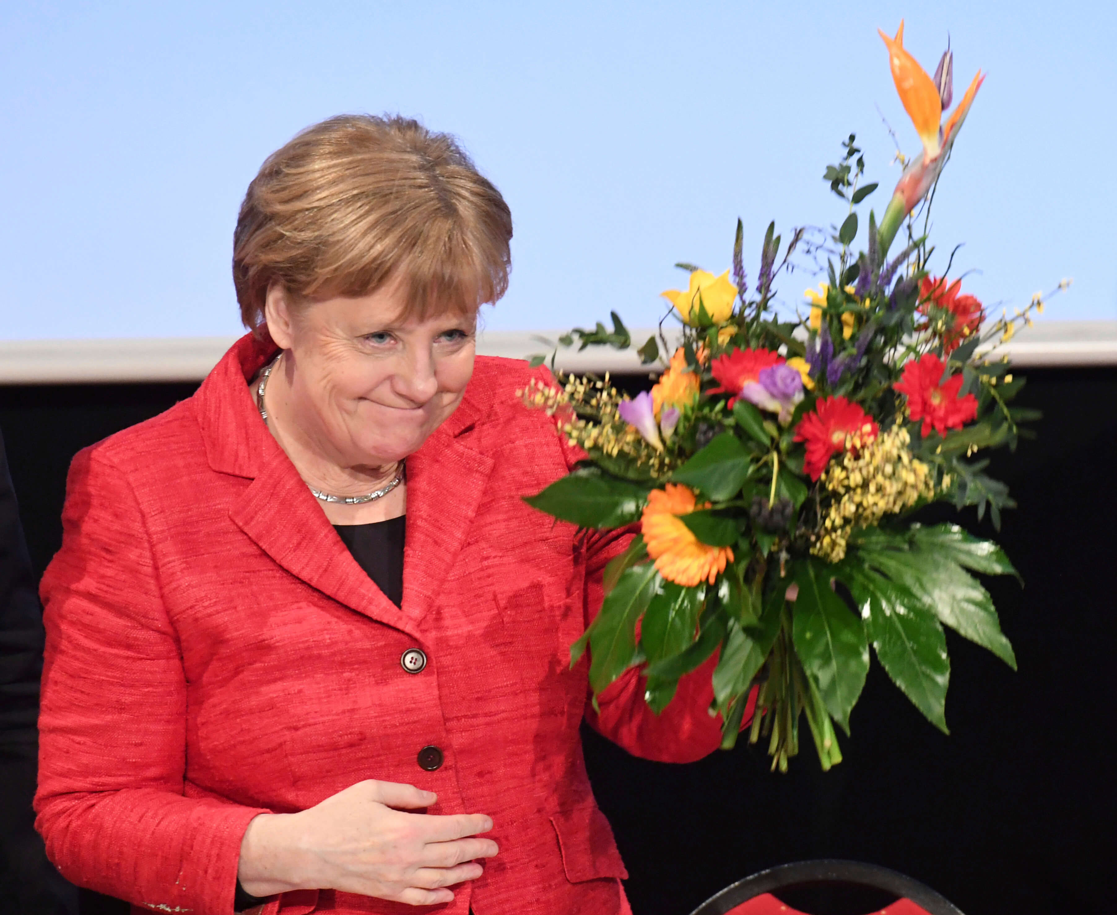 La canciller alemana Angela Merkel sostiene un manojo de flores en una convención de los Demócratas Cristianos en el estado de Mecklemburgo-Pomerania Occidental en Stralsund, Alemania. (AP)