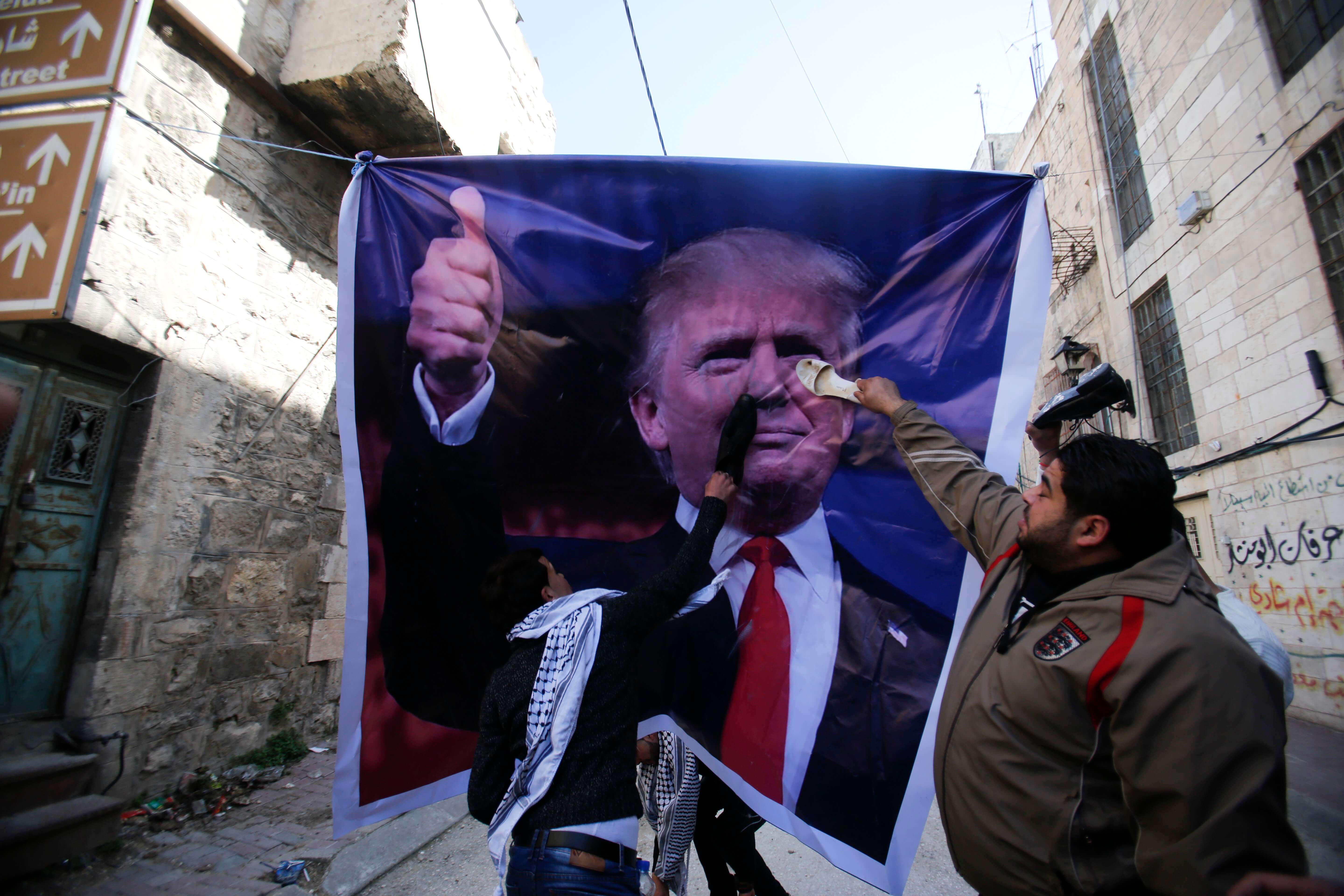 Durante las protestas en la ciudad de Hebrón, algunos palestinos pintaron consignas sobre un cartel del presidente estadounidense Donald Trump . (AP)