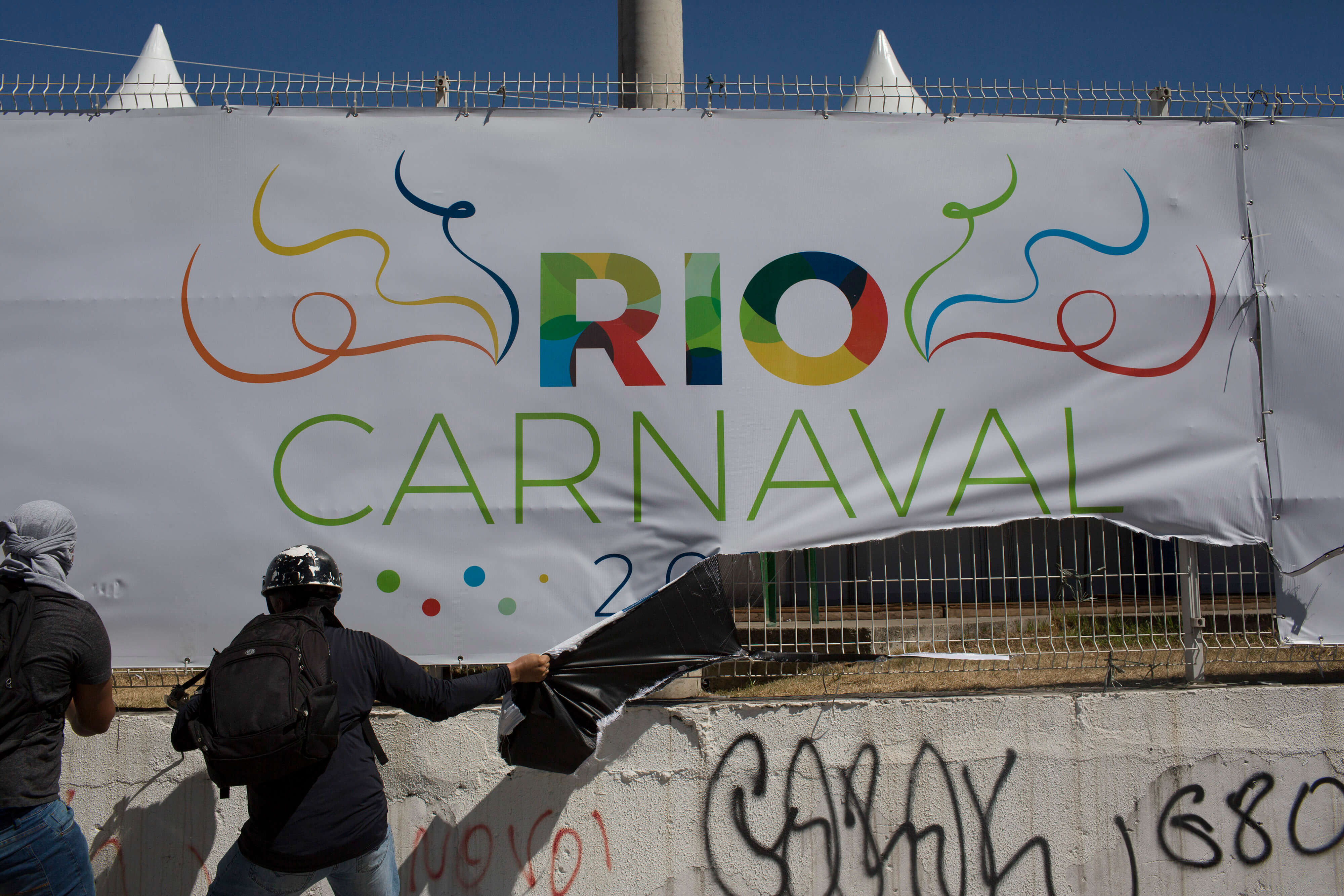 Un manifestante arranca una pancarta de Carnaval de Río junto al Sambódromo durante una protesta contra el gobierno estatal en Río de Janeiro, Brasil (AP)