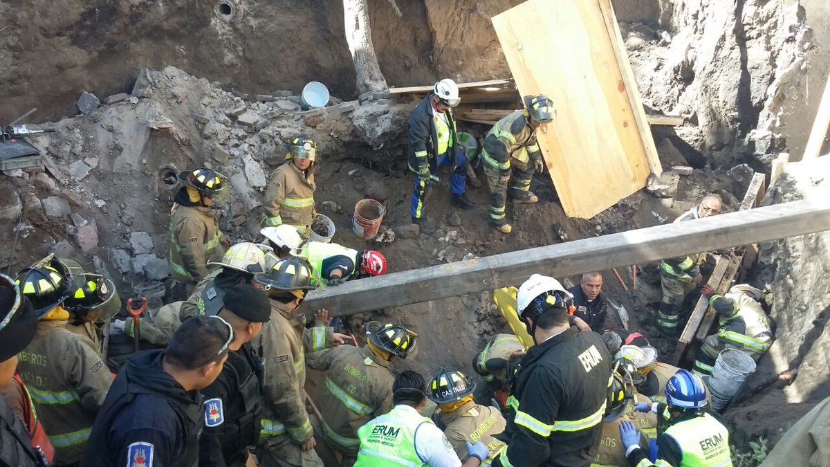 Bomberos trabajan en el rescate de las personas atrapadas por la caída de una barda. (Twitter/@FaustoLugo)