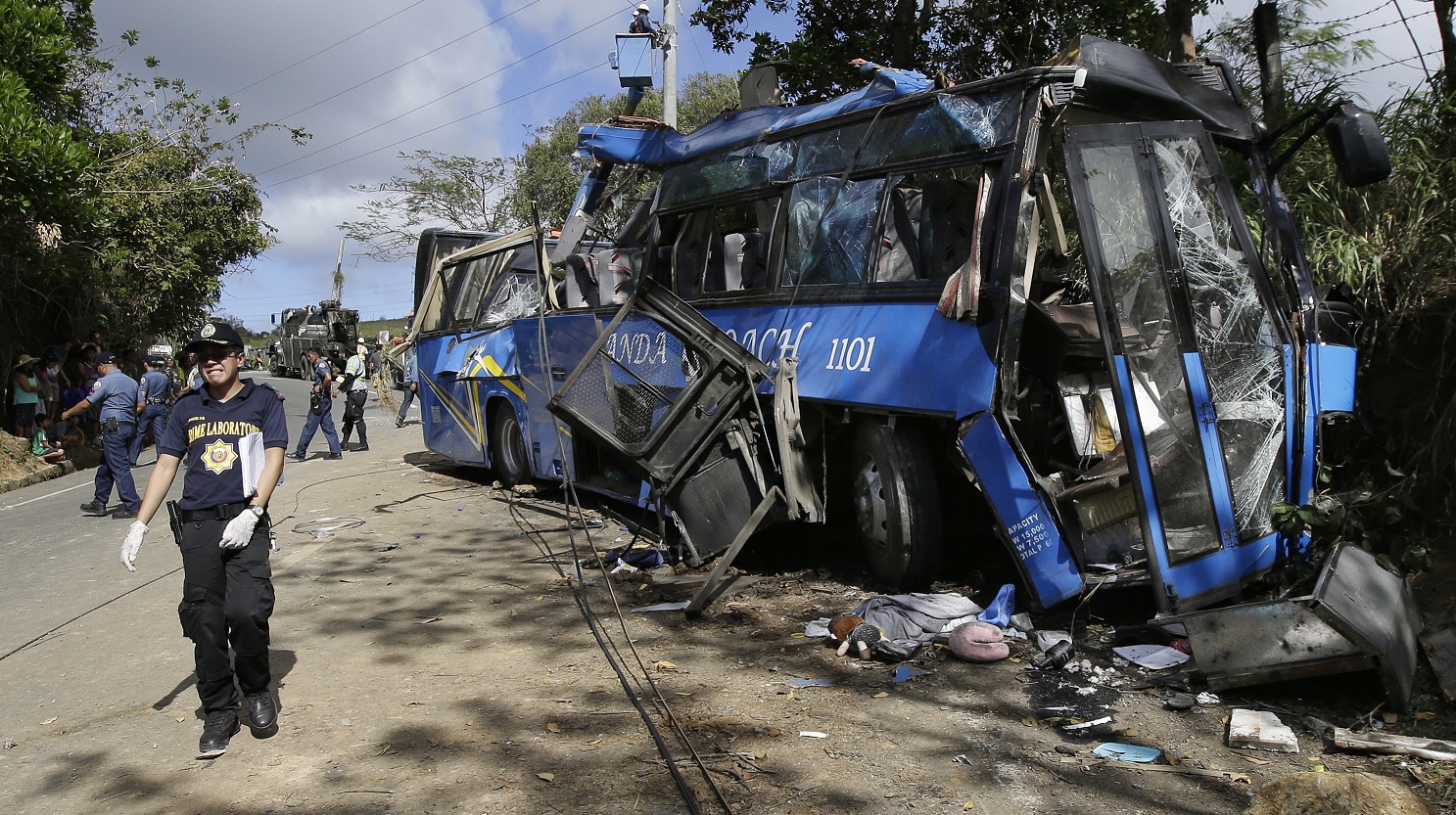 Un investigador de la policía pasa por los restos de un autobús con estudiantes que se estrelló en una carretera al este de Manila, Filipinas (AP)