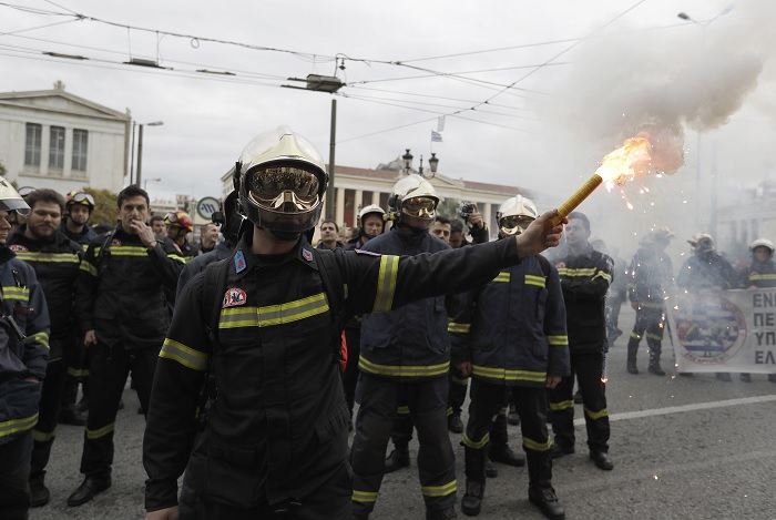 Un bombero sostiene una luz de bengala durante una protesta en el centro de Atenas (AP)