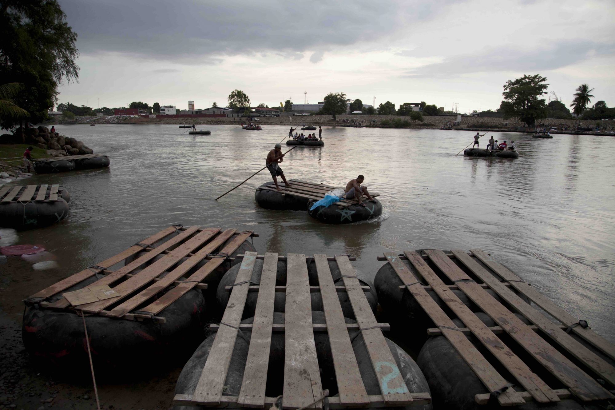Trabajadores guatemaltecos transportan a migrantes centroamericanos en su camino hacia EE.UU. El río Suchiate, que divide Guatemala de México, es un paso en una de muchas rutas usadas por los migrantes.
