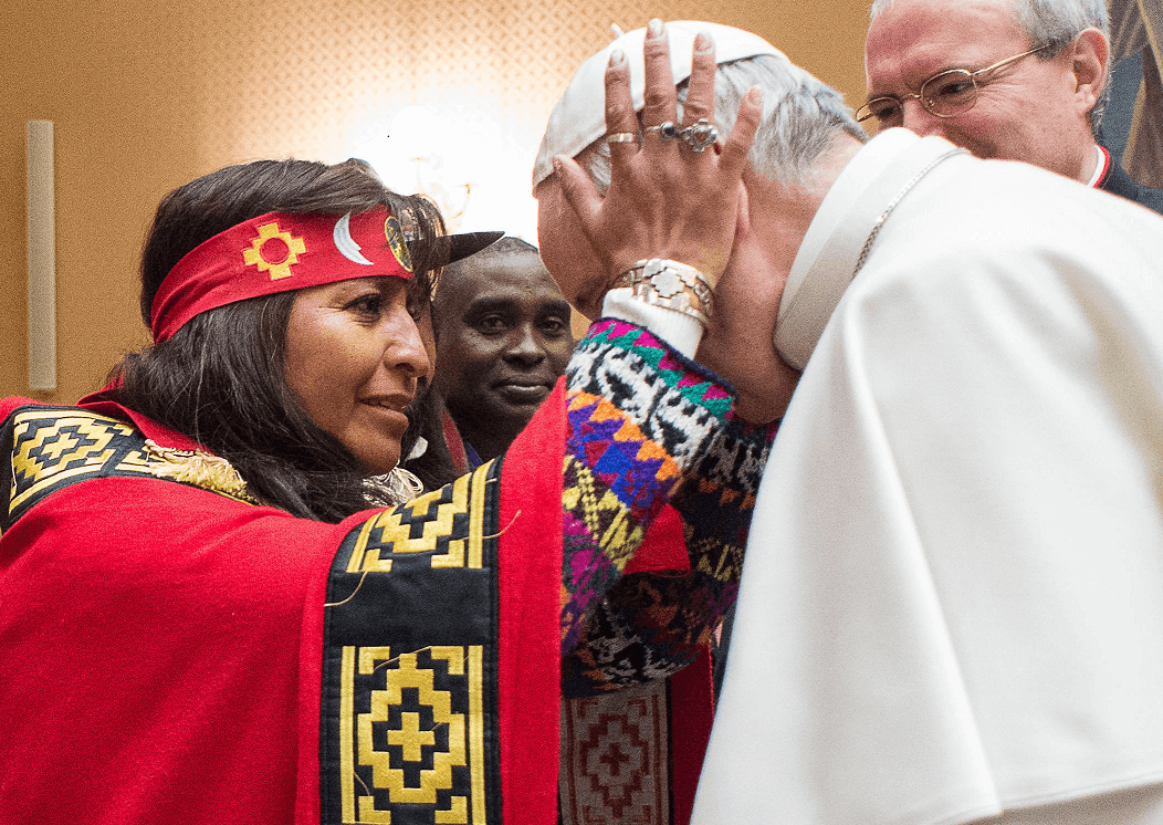 Mujer indígena toma con sus manos el rostro del papa Francisco, durante un encuentro de éste con comunidades indígenas. (AP)