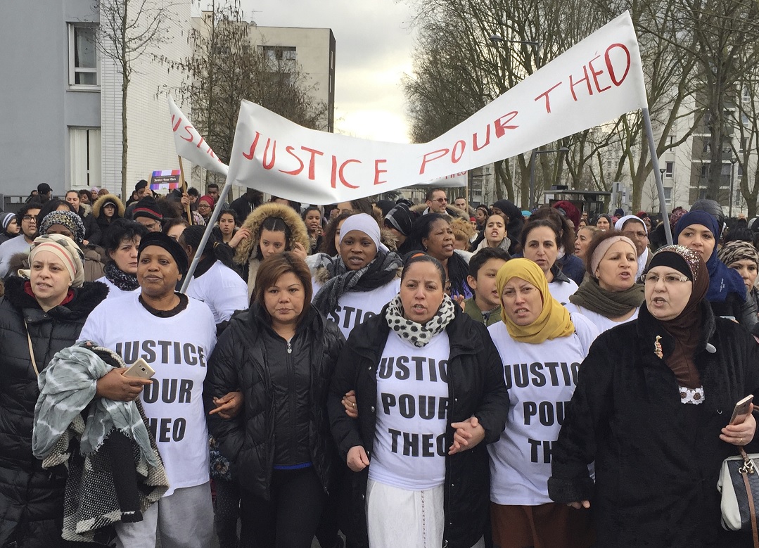 La gente marcha en las calles de Aulnay-sous-Bois, al norte de París, Francia, con un cartel que dice "Justicia para Theo" durante una protesta (AP)