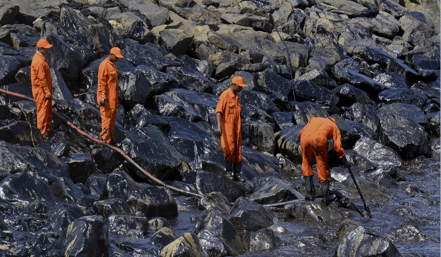 Trabajadores indios limpian el petróleo vertido tras choque de dos buques de carga. (AP)