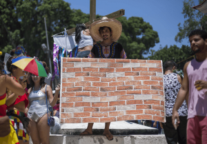 Un joven brasileño sujeta una tela simulando un ladrillo, en alusión al muro que Trump pretende construir en la frontera con México. (AP)