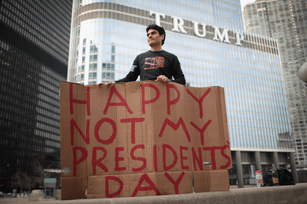 Un manifestante sostiene un cartel asegurando que Donald Trump no es su presidente.