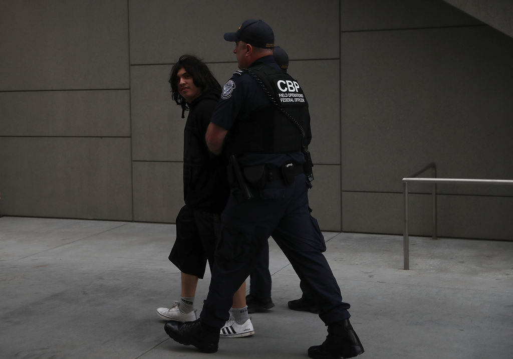 Un oficial de la patrulla fronteriza detiene un joven migrante en San Ysidro, California.