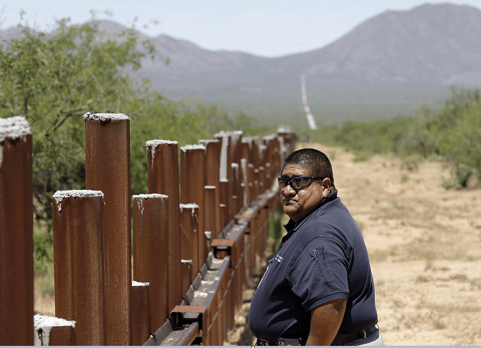 Un sargento de la policía de la etnia tohono o'odham camina junto a la valla fronteriza entre EU y México, en la zona de Arizona. (AP, archivo)