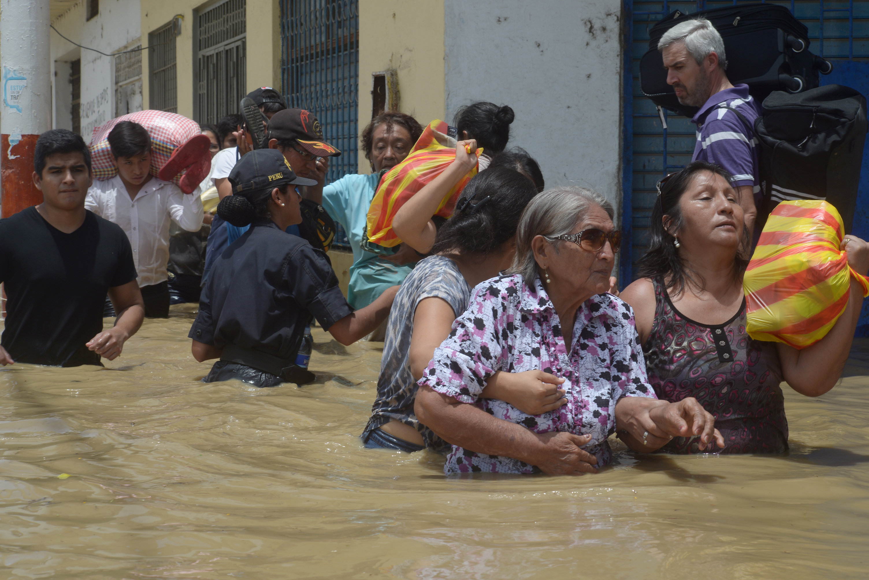 Residentes cruzan una calle inundada después del desbordamiento de ríos por las lluvias torrenciales en Piura, Perú. (Reuters)