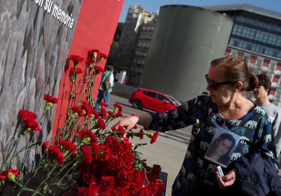 Un pariente de una víctima de los atentados del tren de Madrid coloca una flor afuera de la estación de Atocha en el 13 aniversario de los atentados (Reuters)