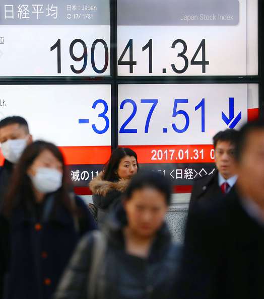 Peatones caminan frente al tablero de la Bolsa de Tokio. (Getty Images)