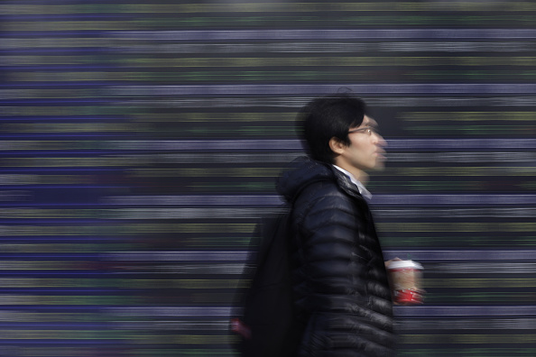 Un peatón camina frente a un tablero electrónico de la Bolsa de Tokio. (Getty Images)