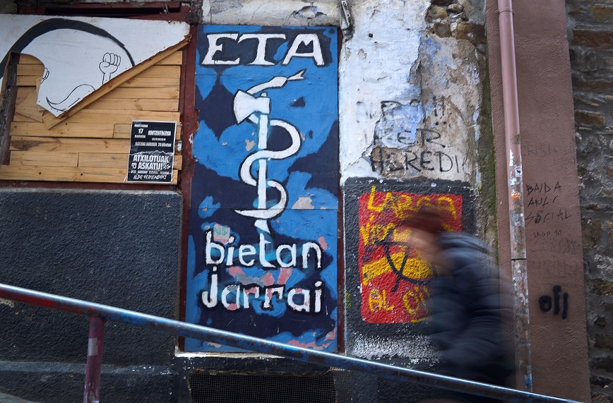 Una mujer pasa por un mural que representa el emblema de la serpiente y el hacha de los separatistas vascos ETA, en la localidad portuaria vasca de Bermeo (Reuters)