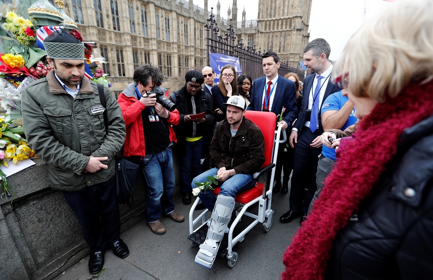 Un hombre herido sostiene una rosa en el puente de Westminster durante un homenaje a las víctimas del atentado de Londres (Reuters)