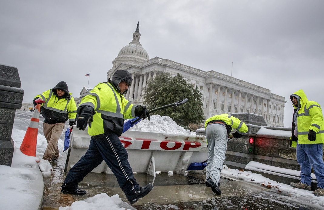 Trabajadores limpian la nieve de una barricada de seguridad en el Capitolio, Washington (AP)