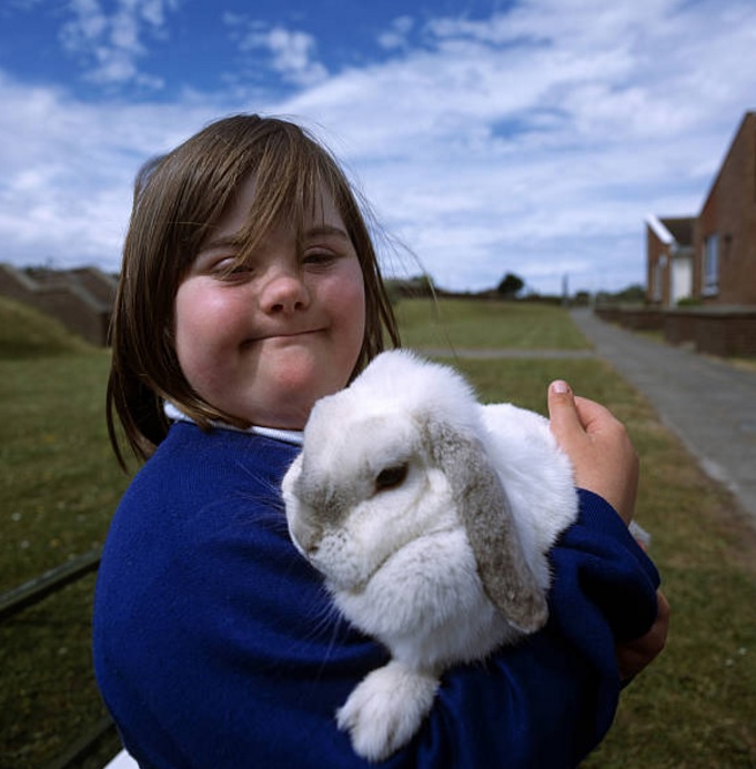 Una niña con Síndrome de Down carga a un conejo de la escuela (Getty Images)