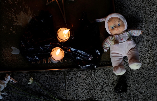 Una muñeca y velas se colocan durante una protesta para exigir justicia a las víctimas de un incendio en el refugio infantil Virgen de Asunción, frente al Palacio Nacional de Guatemala (Reuters)