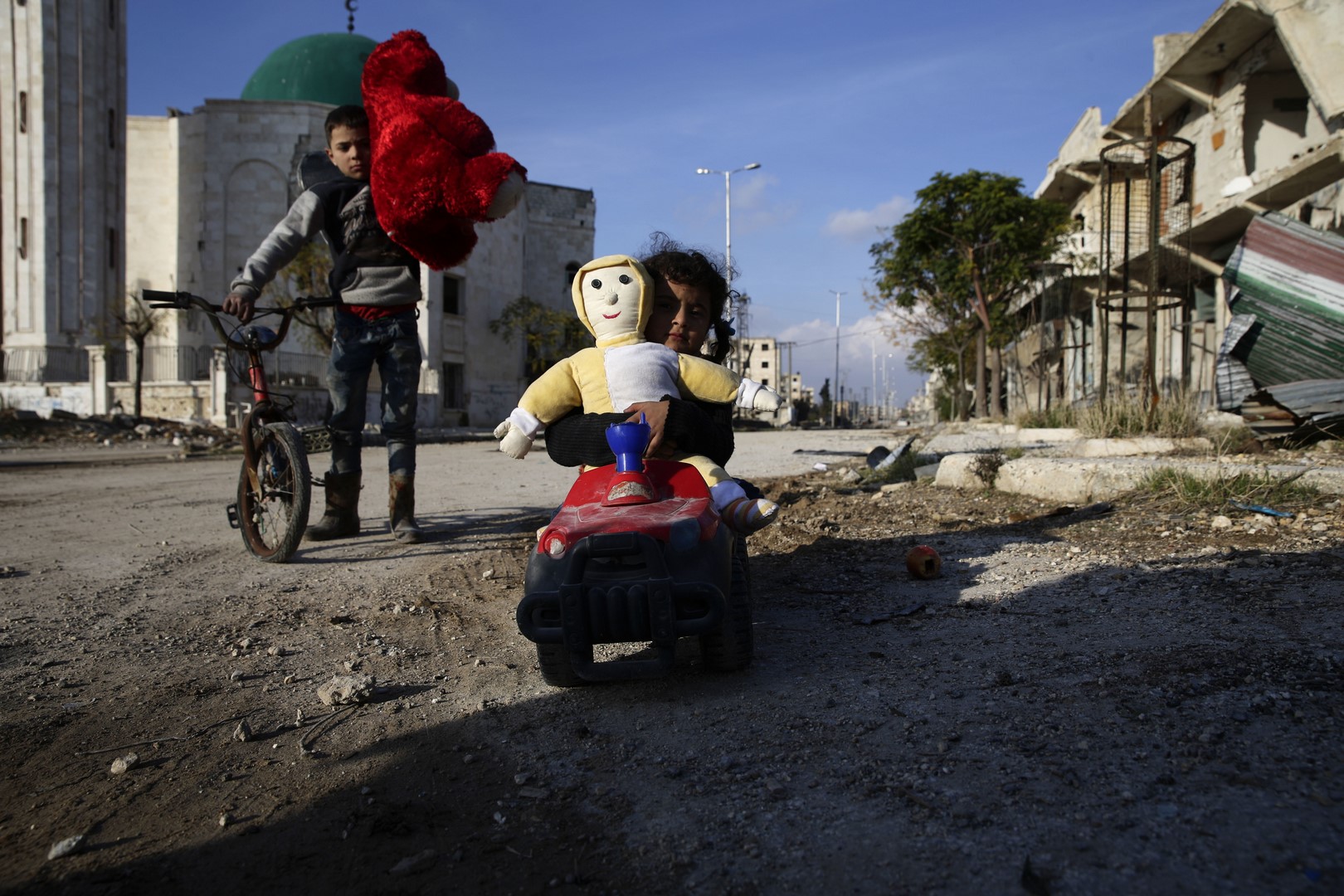 Niños sirios, que fueron desplazados tras un ataque, juegan mientras regresan a su casa en el distrito de Hanano, en Alepo. (Archivo/AP)
