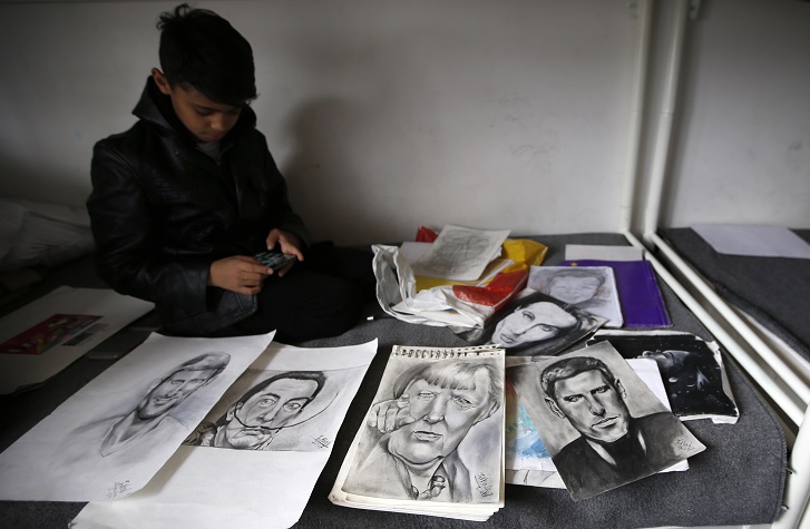 Farhad Nouri muestra los retratos de Novak Djokovic, Salvador Dali y de Angela Merkel, en su habitación en un centro de refugiados en Belgrado, Serbia (AP)