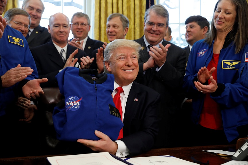 El presidente Donald Trump recibe una camisa de la NASA durante la ceremonia de firma de la S442, la ley de autorización de transición de fondos a la Agencia Espacial de EU (Reuters)