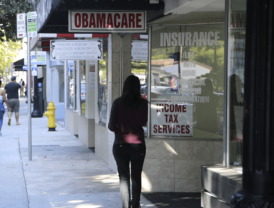 Una mujer camina, en Miami, junto a un letrero de Obamacare, como se le conoce a la reforma sanitaria de Obama. (AP, archivo)