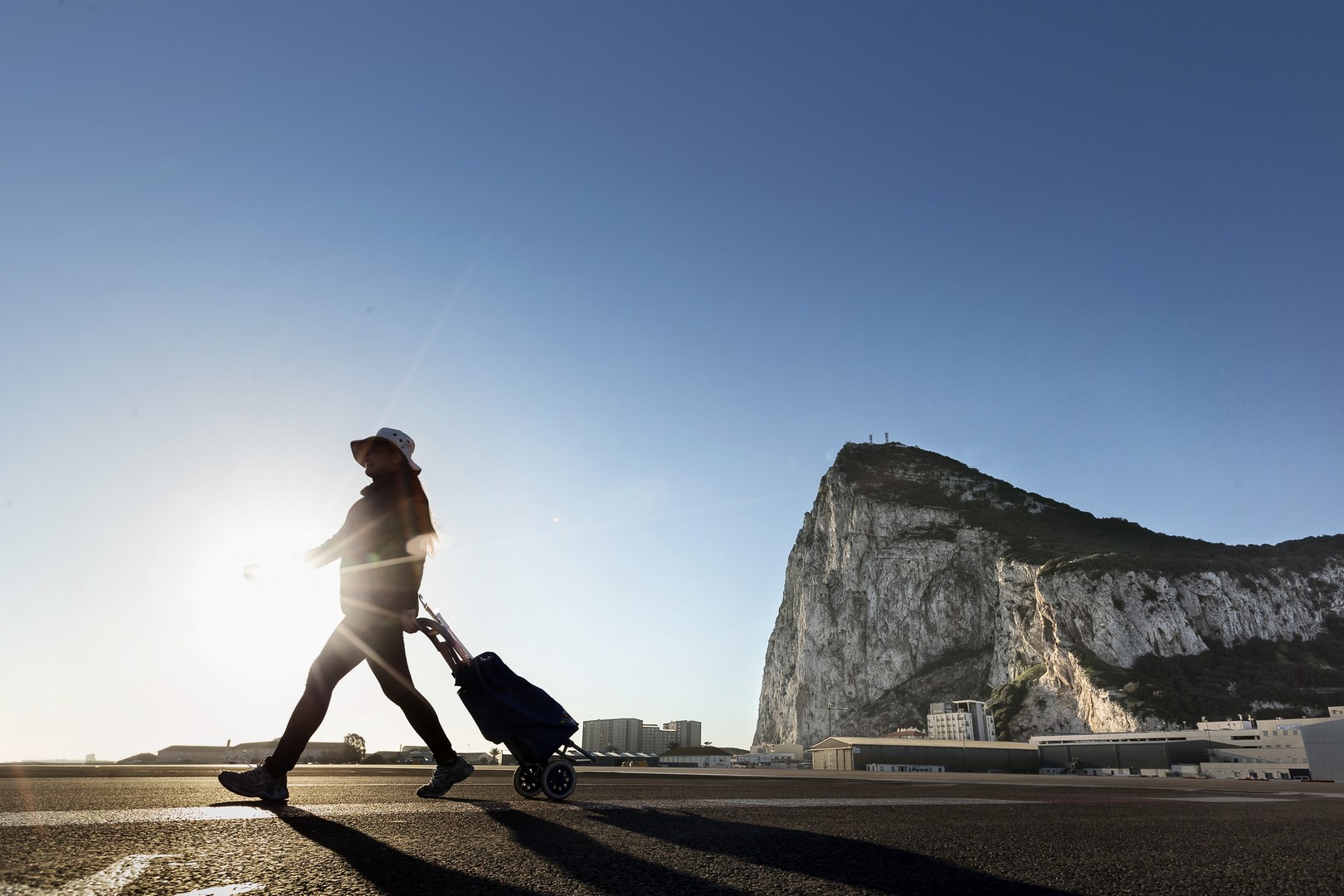 Una mujer camina por el lado español de la frontera entre España y el territorio británico de ultramar de Gibraltar con la roca como telón de fondo. (AP)