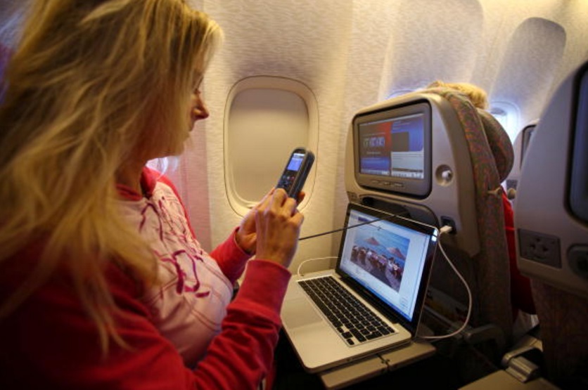 Una mujer trabaja con una computadora portátil y hace una llamada telefónica a bordo de un avión de pasajeros Emirates Airline en Trivandrum, India (Getty Images)