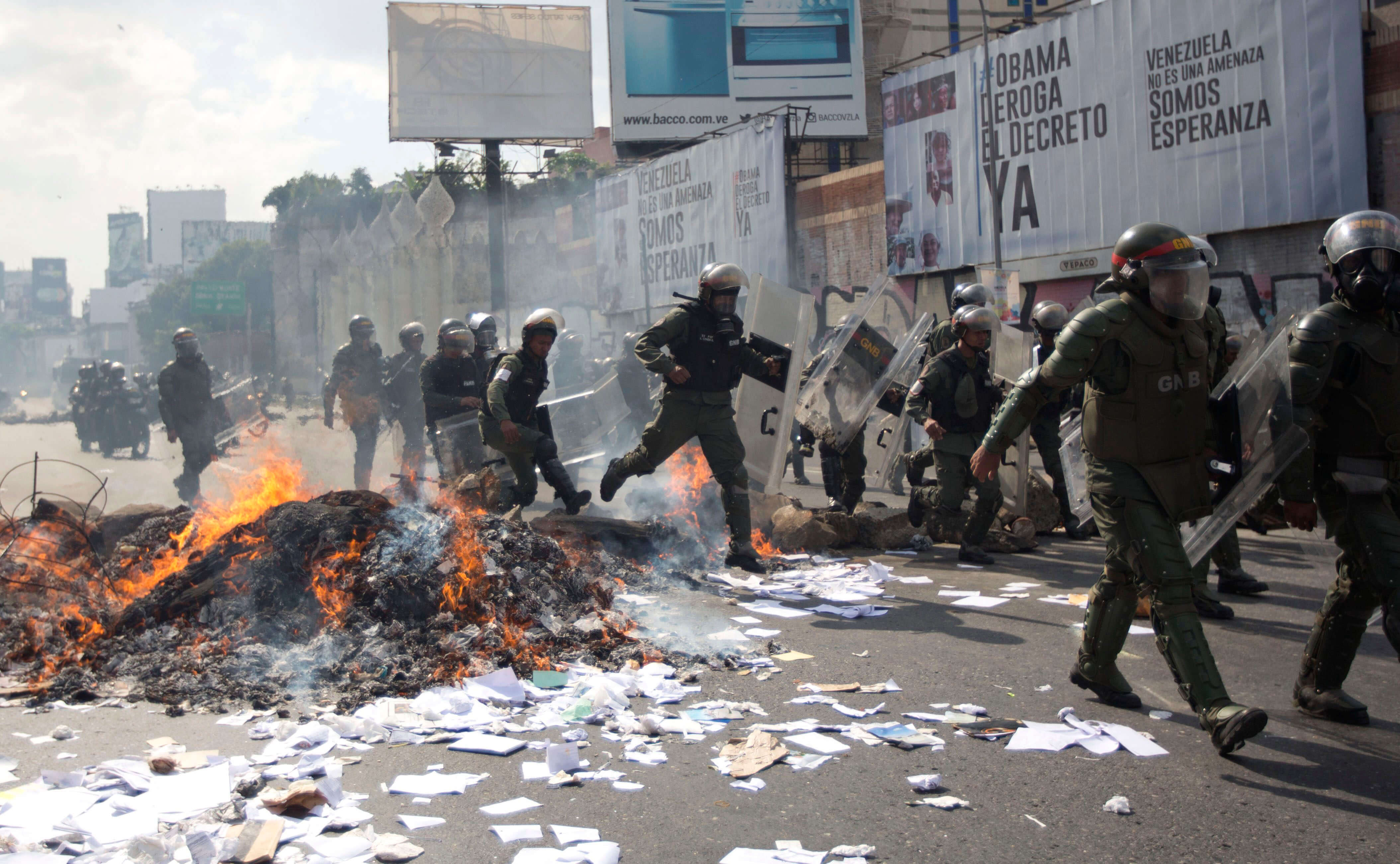 Los funcionarios de la Guardia Nacional Bolivariana se desplazan sobre una barricada en llamas durante una protesta en Caracas, Venezuela. (AP)