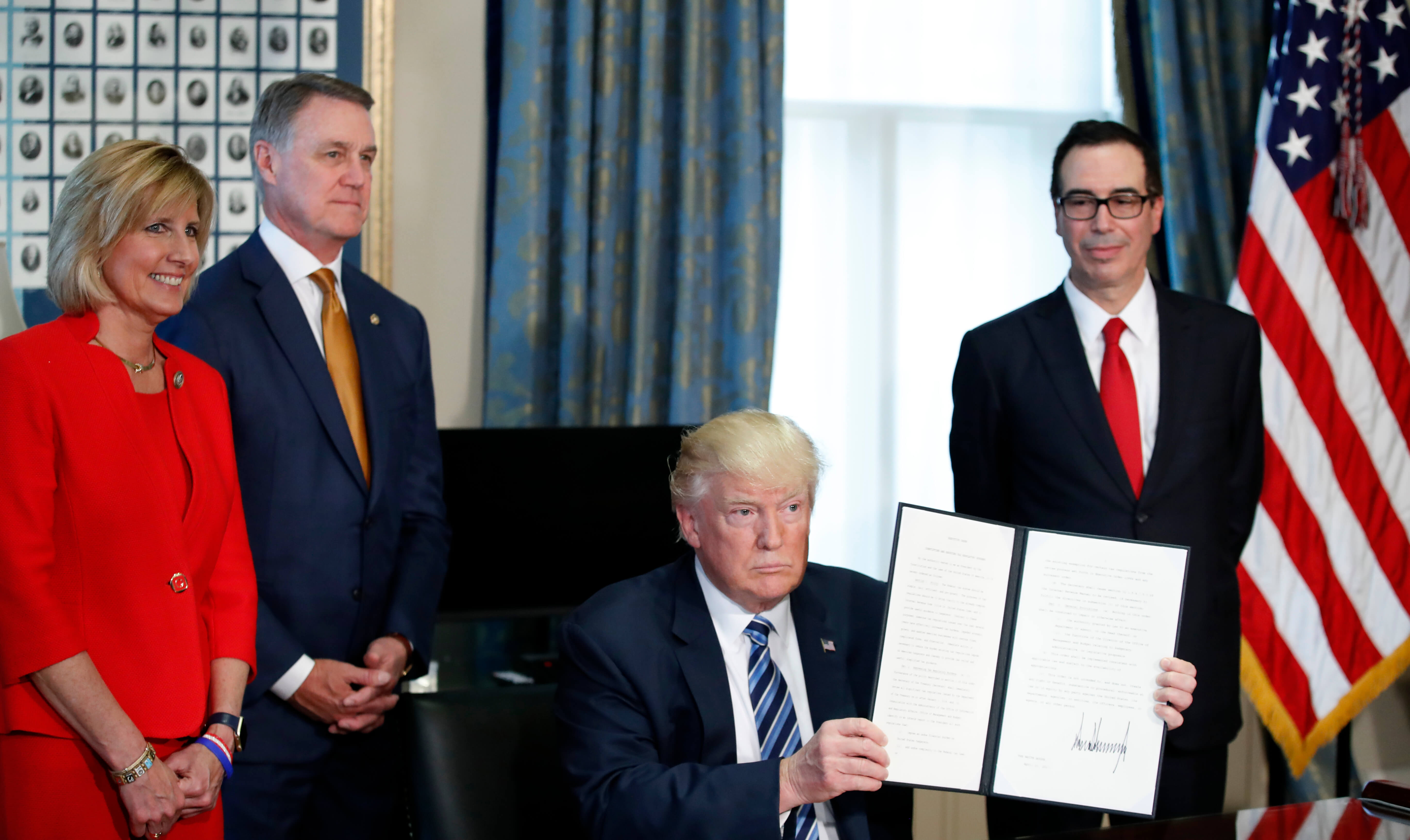 El presidente de Estados Unidos, Donald Trump, acompañado por la congesista Claudia Tenney, el senador David Perdue, y el secretario del Tesoro Steve Mnuchin tras firmar una orden ejecutiva. (AP)