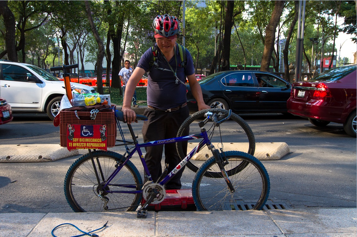 Persona ofrece servicios de reparación de bicicletas sobre Paseo de la Reforma (NTX)