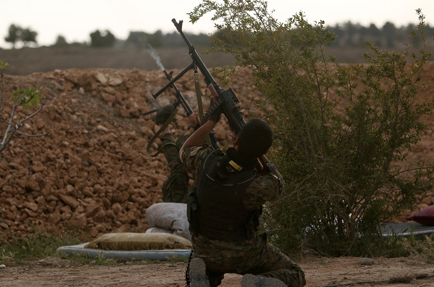 Combatientes contra el Estado Islámico en Siria disparan un arma en la orilla del río Eufrates, al oeste de la ciudad de Raqqa (Reuters)