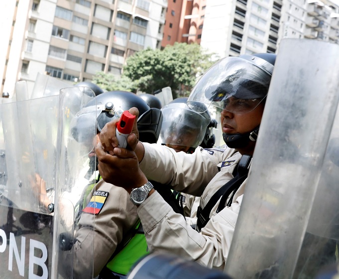 Las fuerzas de seguridad bloquean una calle con escudos antidisturbios y utilizan gas pimienta durante un mitin de la oposición en Caracas, Venezuela (Reuters)