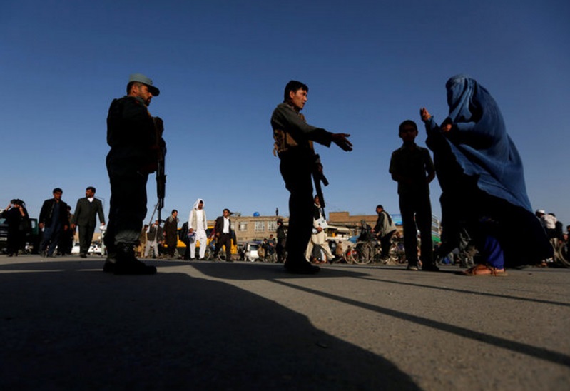 Una familia afgana espera a que los policías desbloqueen el camino cerca del sitio de un atentado suicida en Kabul, Afganistán (Reuters)