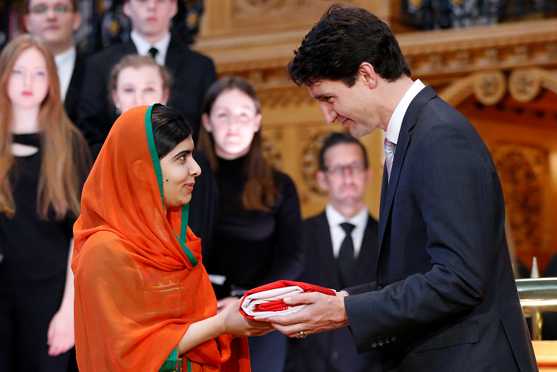 El primer ministro de Canadá, Justin Trudeau, otorga a la ganadora del Premio Nobel de Paz Malala Yousafzai una bandera canadiense durante una ceremonia en el Parlamento en Ottawa (Reuters)