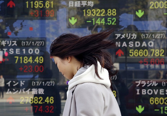 Un peatón camina frente a un tablero con información de los mercados nipones. (AP, archivo)