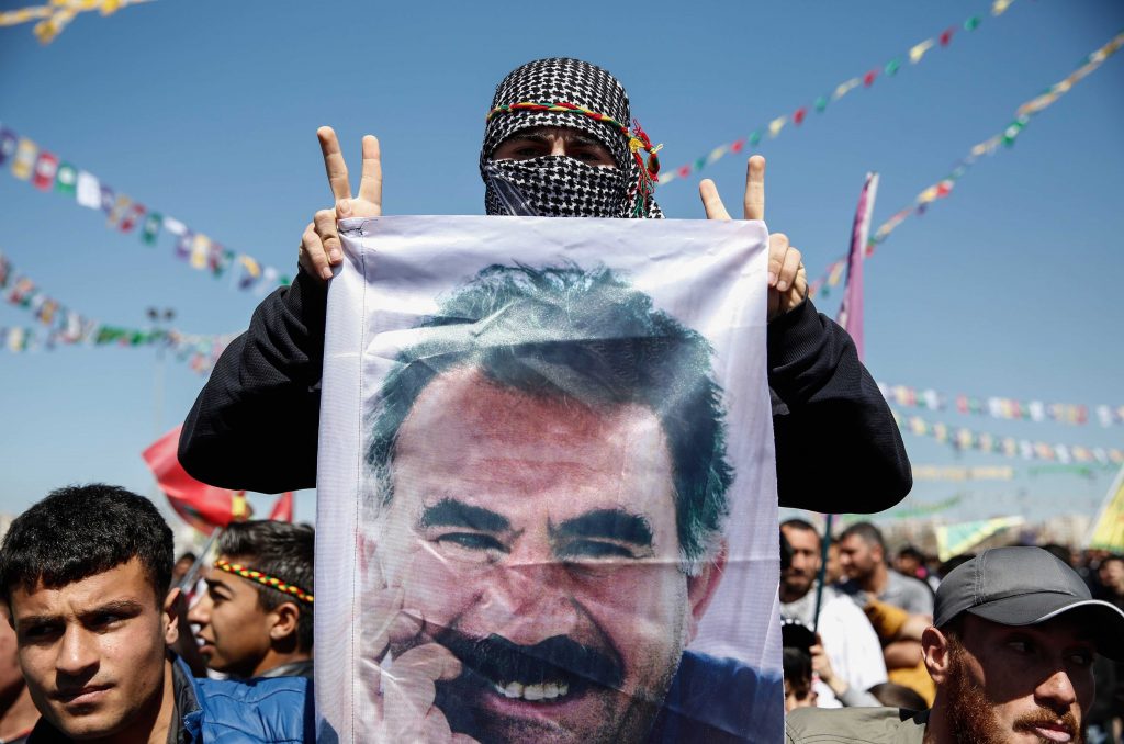 Un hombre kurdo muestra una foto de Abdullah Öcalan en manifestación. 