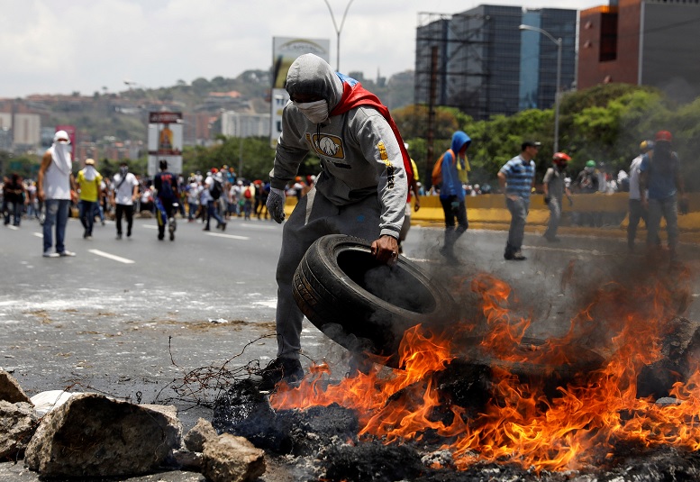 Manifestantes construyen una barricada de fuego en una calle de Caracas, Venezuela (Reuters)